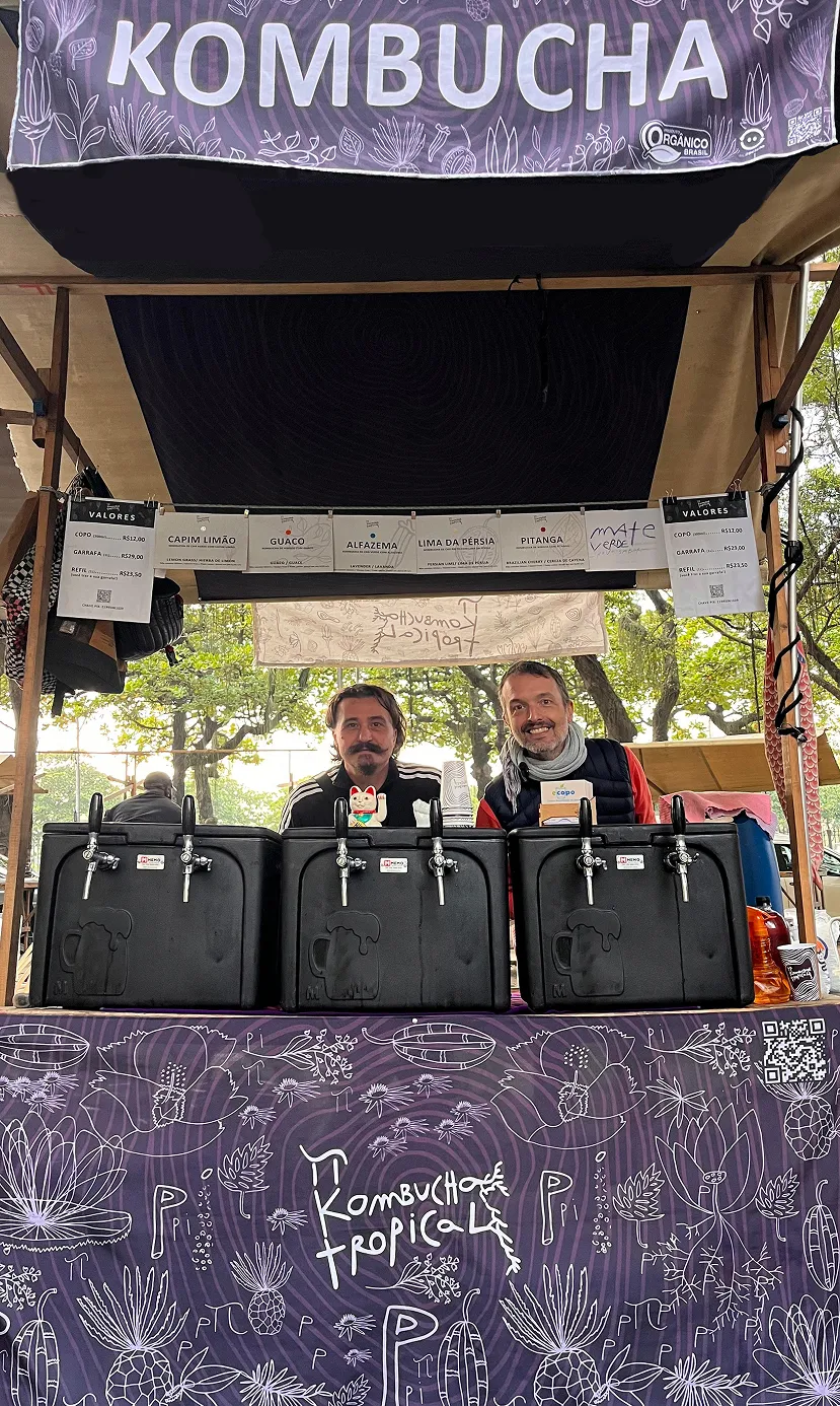 Barraca da Pi Kombucha Tropical em feira livre, com garrafas expostas